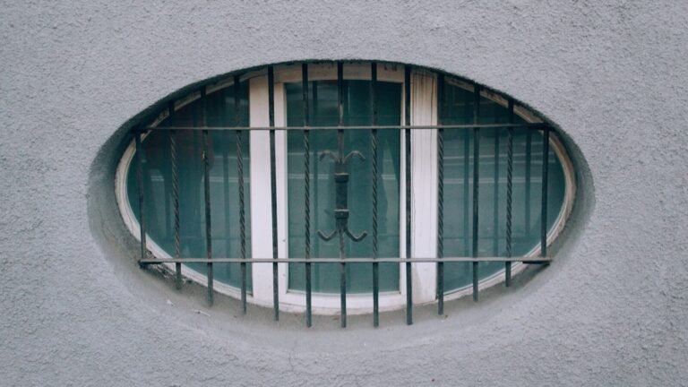 Oval window with metal bars on a textured wall